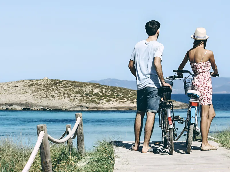 Una pareja con bicicletas en una pasarela de madera junto al mar